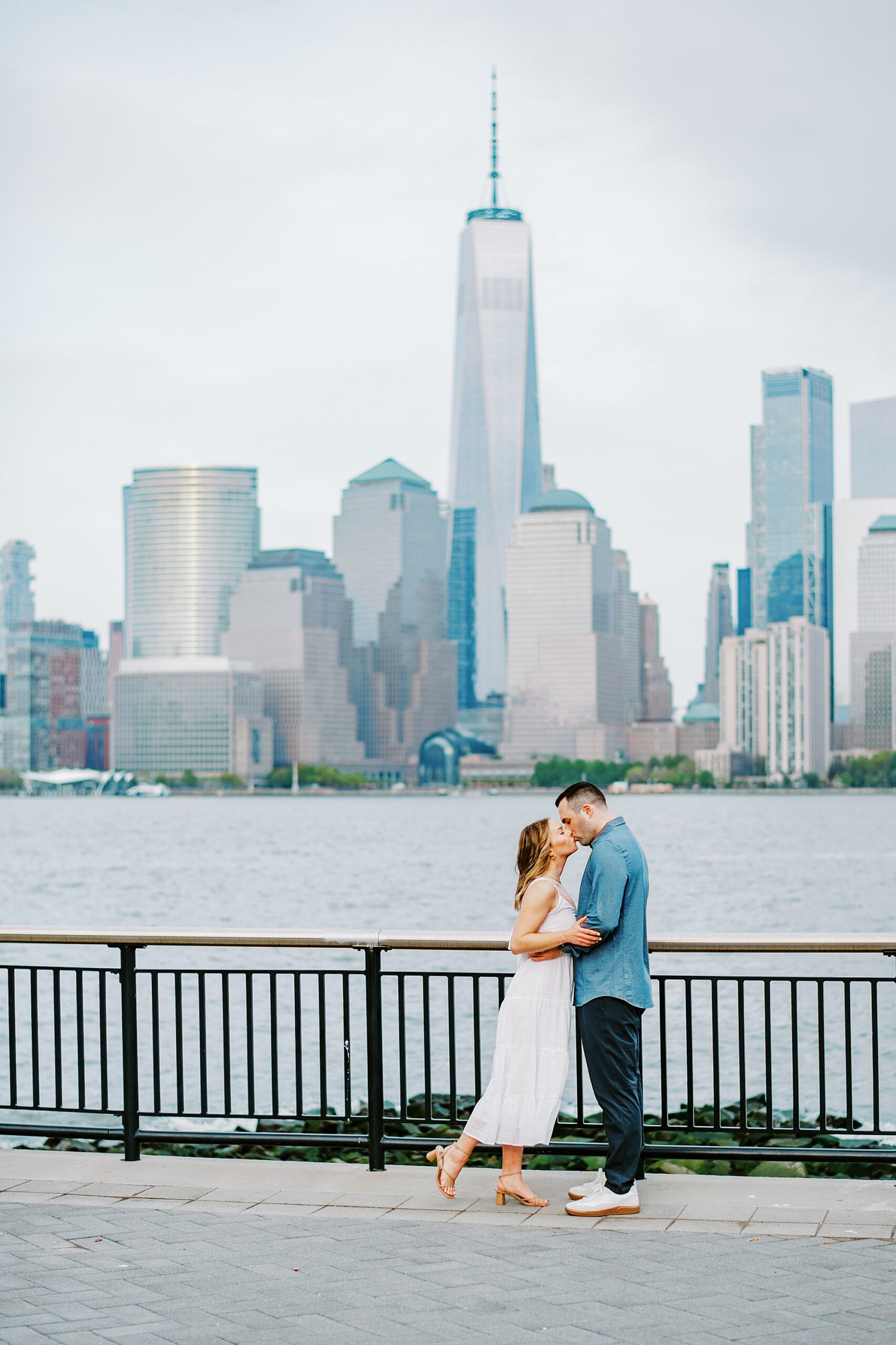 The Jersey City waterfront vantage point of NYC with a sweet couple in the foreground sharing a kiss photo