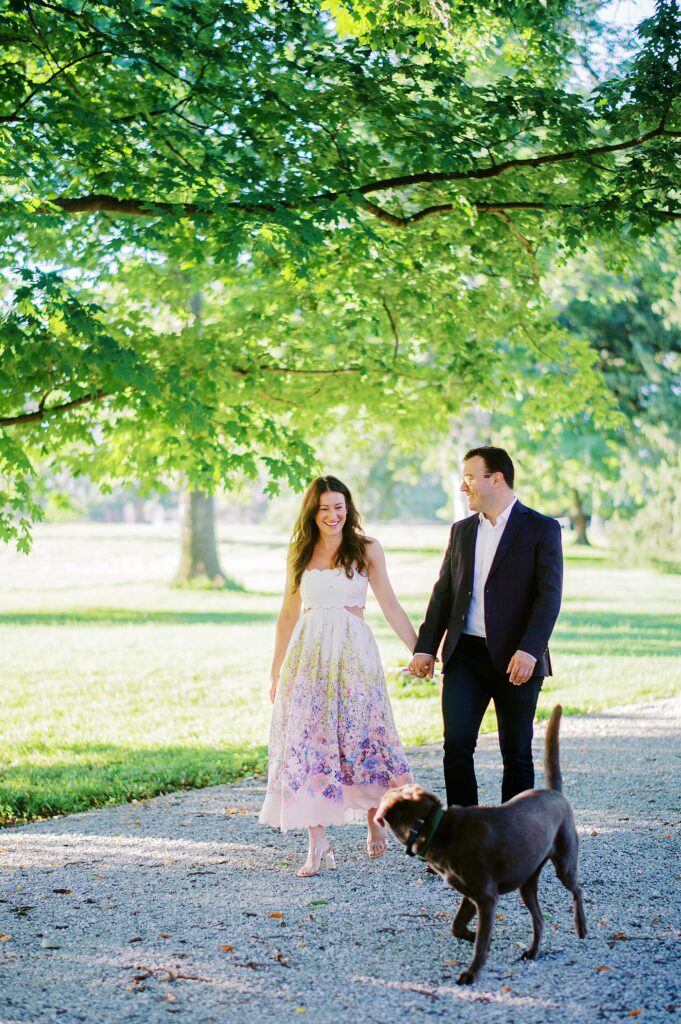 Spring engagement portrait of a couple wearing soft, flowy wardrobe choices in a light-filled outdoor setting.