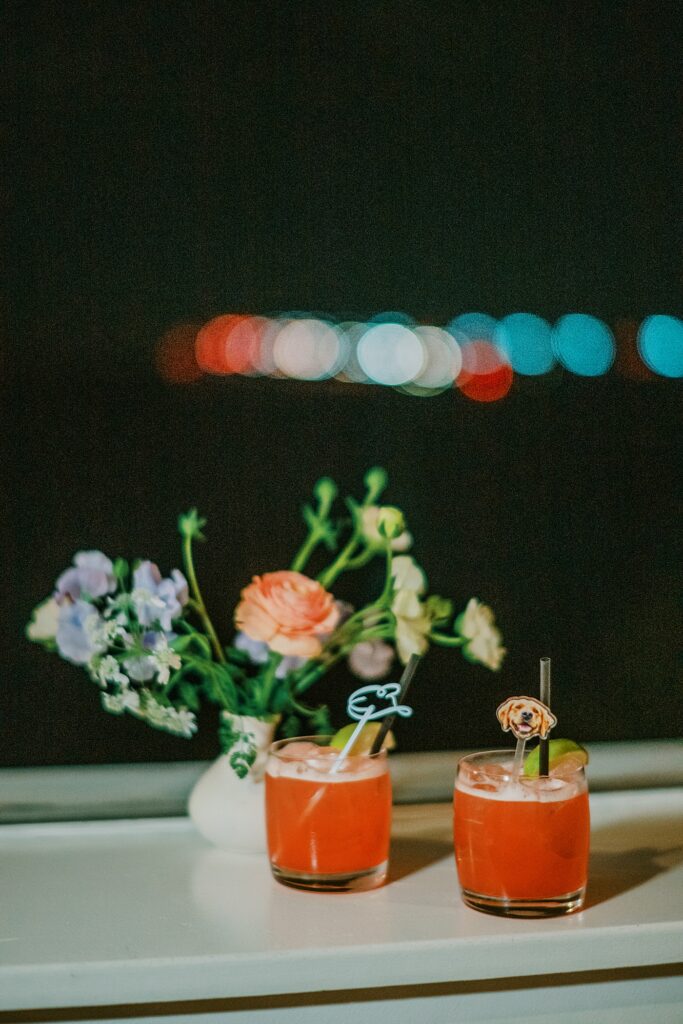 Signature wedding cocktails with custom drink stirrers at reception bar